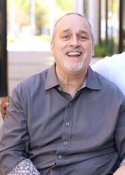 Dan, Giving Care Houston's first client, smiling warmly in a sunlit portrait.